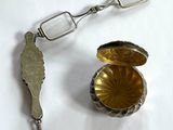 une cuillère en argent et une paire de verres posés sur une table blanche