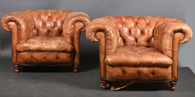 paire de fauteuils en cuir avec accoudoirs capitonnés et repose-pieds, sur un socle noir