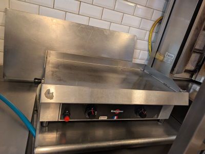 plan de travail en acier inoxydable dans une cuisine professionnelle, sur lequel est fixé un tuyau