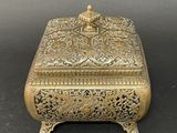 an antique brass box with ornate design on a black background