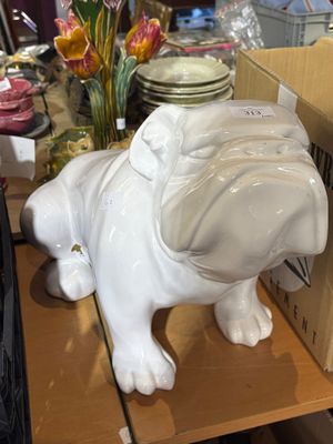 a white dog statue sitting on a shelf next to a box of plates