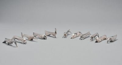 plusieurs figurines d'oiseaux en argent disposées en cercle sur une surface grise
