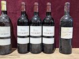 six bottles of wine are lined up on a wooden table