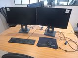 two computer monitors and a keyboard on a desk