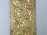 an old brass plate with a design of flowers and leaves on it