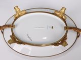 a white plate with gold decorations on it on a white table