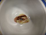 a close up of a bowl with a painting of a woman ' s eye