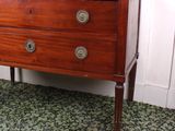 a small wooden chest of drawers in the corner of a room