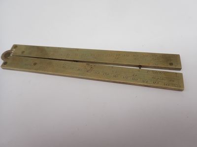une paire de règles en laiton posées sur une surface blanche