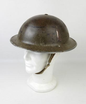 un vieux casque posé sur la tête d'un mannequin, sur une surface blanche
