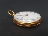 pocket watch on a black surface with a black background