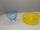 two different colored glass bowls on a white table