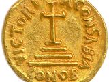 a close up of a gold coin with a cross on it