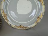 a plate with a gold decoration on it next to a stack of plates