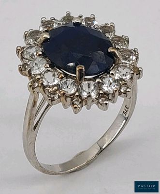 une image représentant une bague ornée d'une grosse pierre bleue entourée de petits diamants blancs