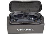 une paire de lunettes de soleil dans un étui, sur fond blanc