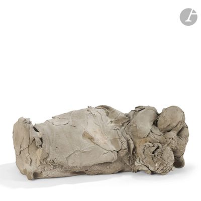 an old statue of a person laying down on a white surface