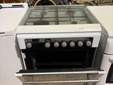 une cuisinière blanche avec un plan de cuisson en verre, placée à côté d'une machine à laver