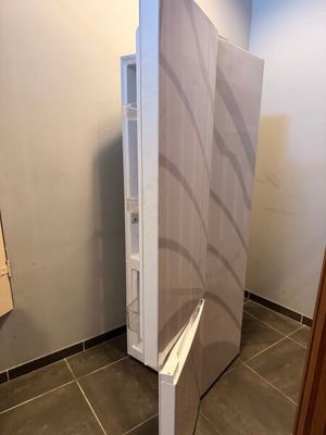 un réfrigérateur dans un coin d'une salle de bains, dont la porte est ouverte