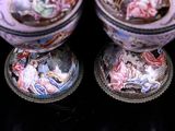 two vases with pictures on them on a black surface