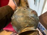 someone is holding a brass vase in their hand in a living room