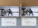 two metal figurines of two men sitting on a bench