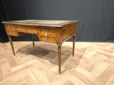 a wooden desk with a marble top on a parquet floor