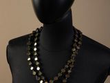 a black mannequin with gold and black beads on a mannequin