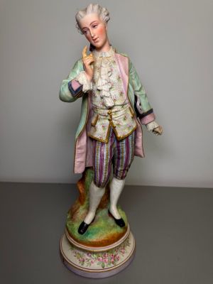 a figurine of a man with a pink coat and purple pants
