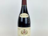 a bottle of red wine sitting on top of a white table