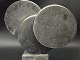 une sculpture composée de trois disques posés sur un socle, sur fond noir