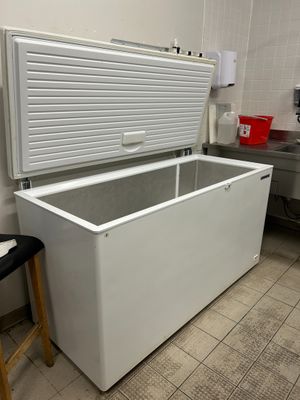 un congélateur coffre blanc posé dans une cuisine à côté d'un tabouret
