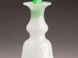 a white vase with a green flower inside of it