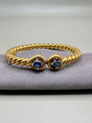 un gros plan d'un bracelet en or orné de deux pierres bleues