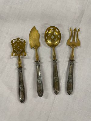 quatre cuillères en argent et en or et une fourchette posées sur une nappe blanche