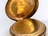 a gold pocket watch sitting on a white surface