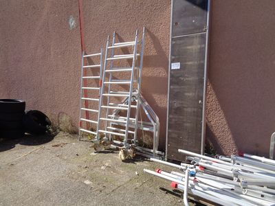 a ladder leaning against a building next to a pile of pipes