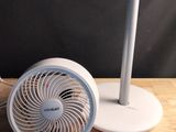 un petit ventilateur posé sur une table, à côté d'un téléphone
