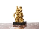 une statue en or représentant une femme et un homme, posée sur une table en marbre
