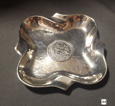 a silver plate with a coin on it on a table