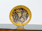 une assiette jaune sur laquelle est représenté un tigre, posée sur une table