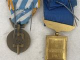 two medals are shown on a white surface with a blue and gold ribbon