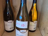 three bottles of wine sit on a wooden shelf in a wine cellar