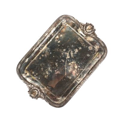 un plateau en argent comportant un miroir, posé sur une surface blanche