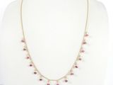 un collier en or orné de pierres roses et de perles, posé sur un mannequin