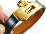 a person holding a black leather bracelet with a gold buckle