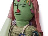 a green doll with a pink head and a pink scarf