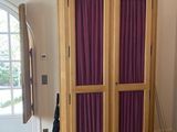 une grande armoire en bois avec des rideaux violets dans une pièce
