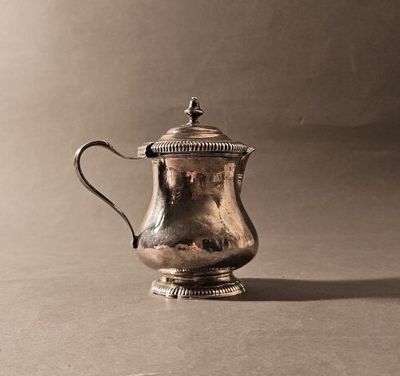 une cafetière ancienne en argent posée sur une table