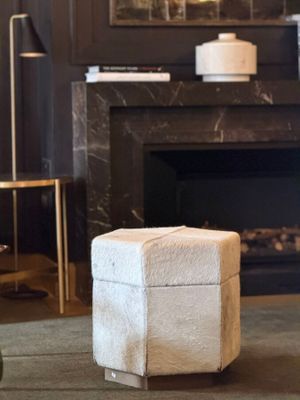 a white ottoman sitting in front of a fireplace in a living room